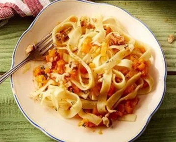 Bandnudeln mit Butternut-Kürbis und Walnüssen auf einem Teller angerichtet