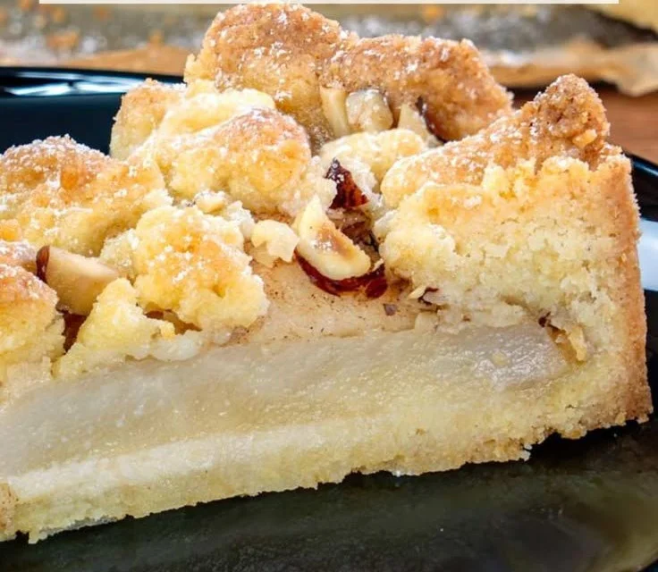 Birnenkuchen mit Streusel auf einem Teller serviert, dekoriert mit frischen Birnen