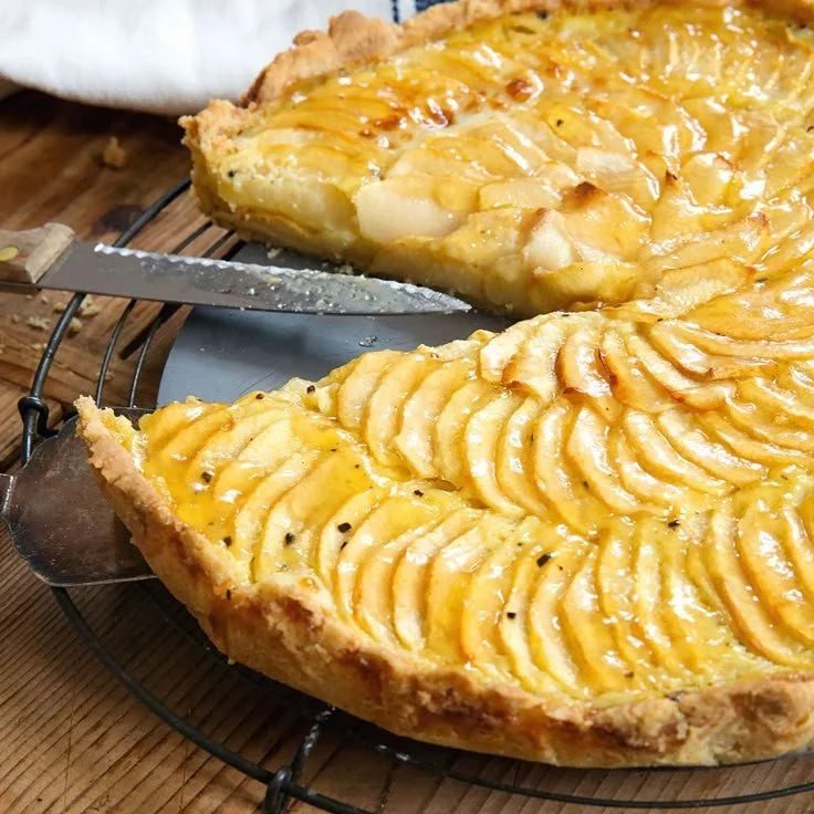 Französische Apfeltarte mit frischen Äpfeln auf einem rustikalen Holzbrett
