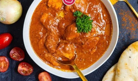 Indisches Butter Chicken nach Original-Rezept serviert mit Reis und Naan-Brot.