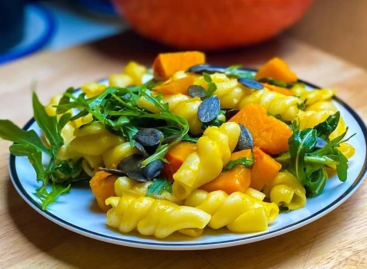 Kürbis-Pasta mit Rucola serviert auf einem weißen Teller