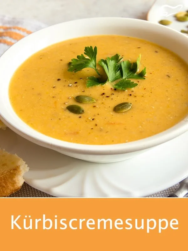 Cremige Kürbiscremesuppe in einer Schale, dekoriert mit Kürbiskernen und Sahne.