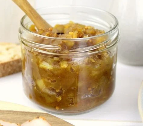 Leckeres Apfel-Zwiebel-Chutney in einem Glas, serviert mit frischem Brot.