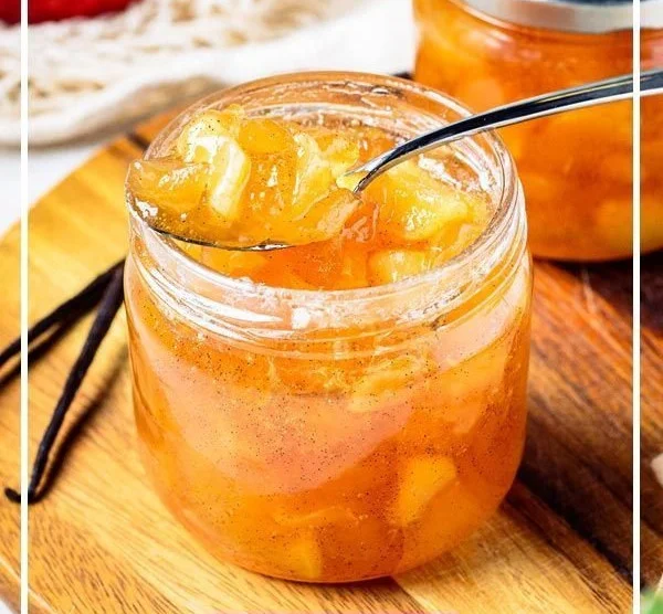 Selbstgemachte Apfelmarmelade in einem Glas mit frischen Äpfeln