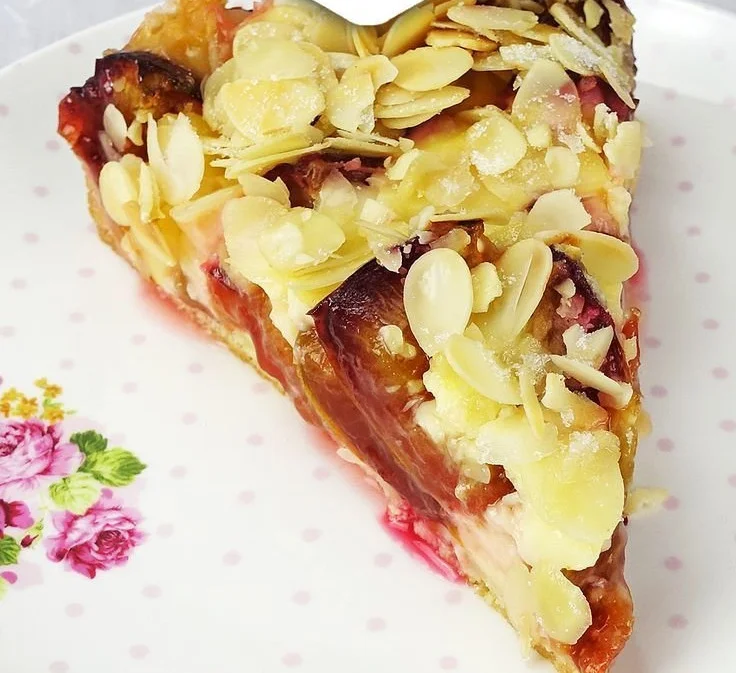 Zwetschgenkuchen mit Pudding und Mandelkruste auf einem Teller