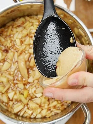 Bratapfelmarmelade mit Nüssen und Marzipan auf einem Holzbrett