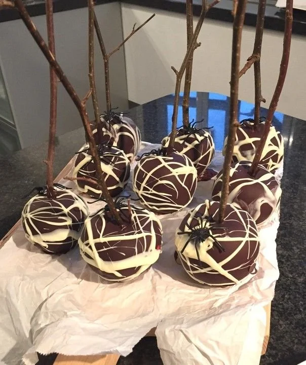 Halloween-Schoko-Äpfel am Stiel mit Spinnweben für Halloween-Dekoration