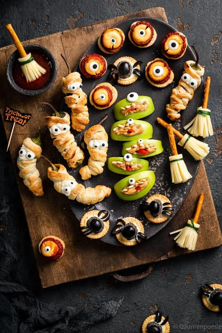 Schaurige Halloween Käse-Platte mit verschiedenen Käsesorten und Halloween-Dekorationen.